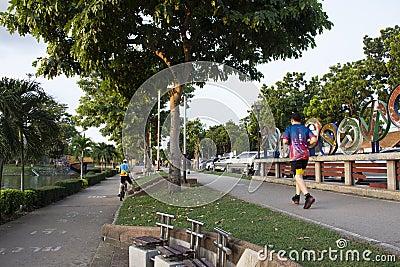 Asian thai people and foreign travelers walking jogging exercise biking bicycle on pathway around pondside in dusk time at Nong Editorial Stock Photo