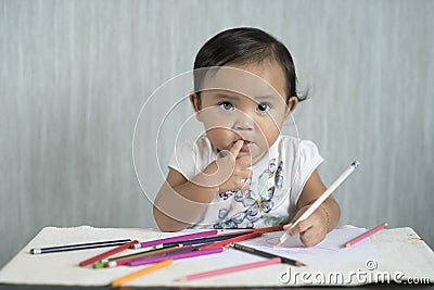 Asian toddler / baby girl is having fun learning to use pencils. Stock Photo