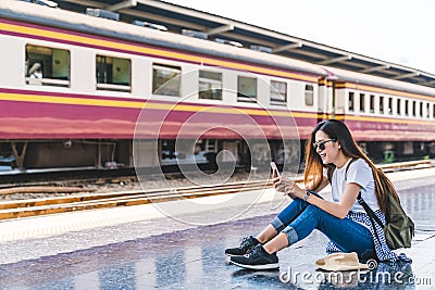 Asian tourist teenage girl at train station using smartphone map, social media check-in, or buy ticket booking Stock Photo