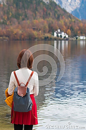 Asian tourist traveller girl from back standing at Hallstatt lake Austria in autumn; freedom peaceful relax concept Stock Photo