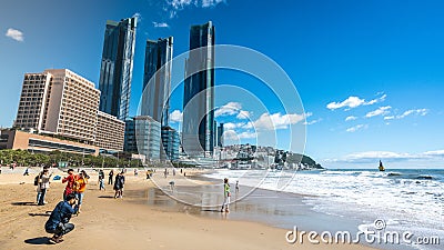 Asian tourists on Haeundae beach on sunny autumn day and modern city skyscrapers of Haeundae LCT The Sharp Busan South Korea Editorial Stock Photo