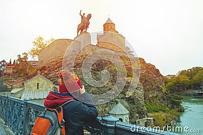 Asian travel backpacker lady in winter suit use camera take photo of Statue of King Vakhtang Gorgasali,one of travel destination Stock Photo