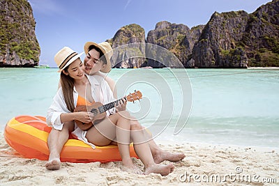 Asian traveller couple sitting and see sunset togather on the beach with longtail boat background Stock Photo