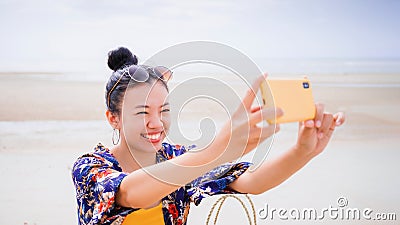 Asian traveller woman sit back and relax on the beach by the sea background on weekend vacation.Concept of happy solo travel Stock Photo