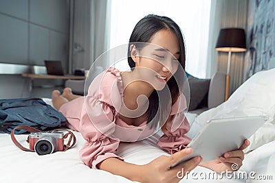 Asian traveller woman take travel bag sleep on the bed and check masage in her mobile Stock Photo