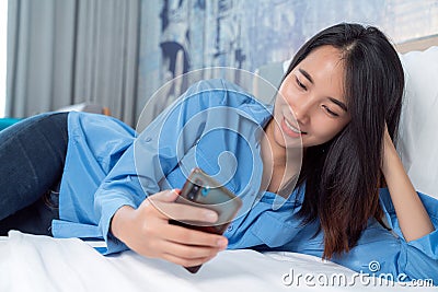 Asian traveller woman take travel bag sleep on the bed and check masage in her mobile Stock Photo