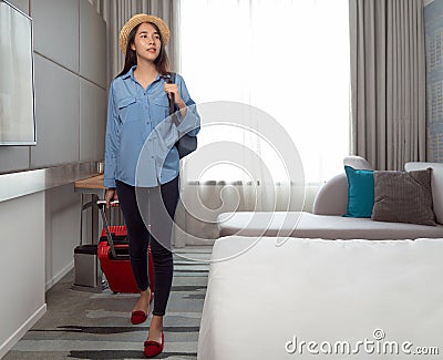 Asian traveller woman take travel bag and walking check out from her hotel room Stock Photo