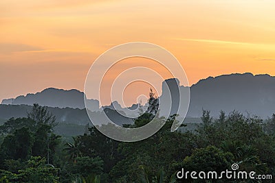 Landscape with foggy hazy mountains silhouettes and tropical nature on orange sunset Stock Photo