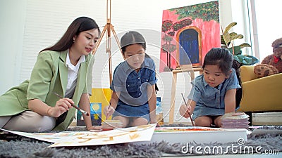 Asian two siblings learning study watercolor paint together at home. Teacher or parent teach student or daughter drawing paint Stock Photo