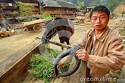 Asian Village, Rural Chinese peasant farmer is holding horse-collar. Editorial Stock Photo