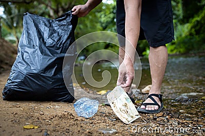 Asian volunteer is picking up trash waste rubbish with garbage bag,medical masks of tourists in national park,problem of littering Stock Photo