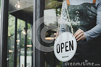 Asian waitress staff woman wearing apron turning open sign board on glass door in modern cafe coffee shop, hotel, cafe restaurant, Stock Photo