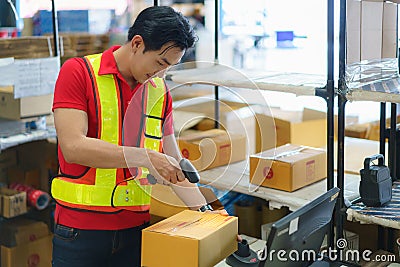 Asian warehouse man worker with computer and barcode scanner in warehouse scan at box prepare deliverly to customer Stock Photo