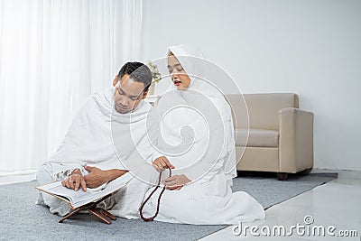 Asian wife and husband praying with Al-Qur`an and tasbih Stock Photo