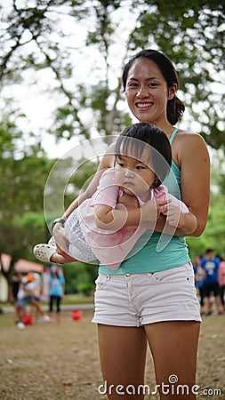 Asian woman carrying toddler and participating in family games Stock Photo