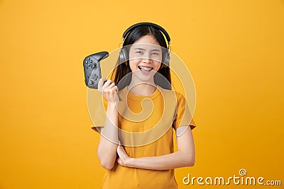 Asian woman in casual yellow t-shirt and playing video games using joysticks with headphones. Stock Photo