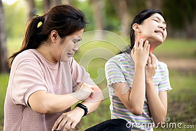 Asian woman and child girl itching her arm and neck from insect bites,mosquito bite,risk of dengue fever,malaria,itching of skin Stock Photo