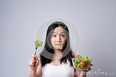 Asian woman confused with eating salad isolated over white background Stock Photo