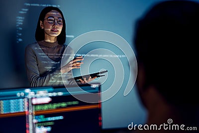 asian woman developers collaborating on a coding project, with one member presentation at code projected on the wall while the Stock Photo