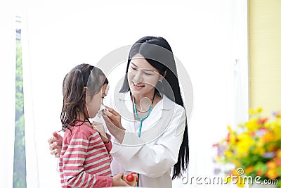 An Asian woman doctor examined a fever for a little girl in the hospital. Stock Photo
