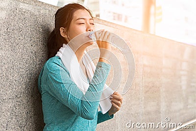 Asian woman drinking water to rehydrate to avoid heat stroke after running outdoors in the summer Stock Photo