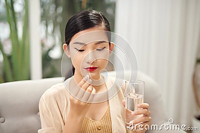 Asian woman eat medicine pills to increase immunity with water and feel better at home Stock Photo