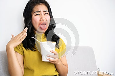 Asian woman eating very hot and spicy noodle from a cup her mouth and tongue burning and red Stock Photo