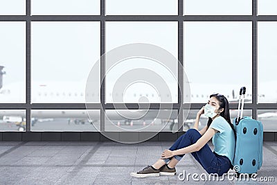 Asian woman with a face mask sitting with a suitcase Stock Photo