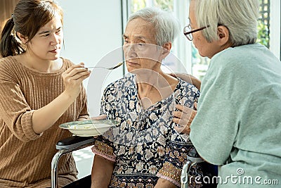 Asian woman feeding tired senior patient,anorexia,eat less food,depressed female elderly suffer from depressive disorder,symptoms Stock Photo