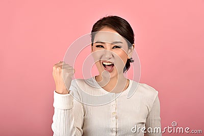 Asian woman feeling happy and excited on accomplish success on pink background. Stock Photo