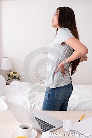 Asian woman freelancer back pain from long time working at home. Stock Photo