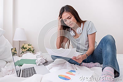 Asian woman freelancer headache about paperwork on bed with laptop in bedroom.work at home concept.stress working. Stock Photo