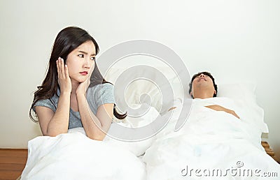 Asian woman getting disturbed and annoy with man sleep and snoring on bed. Bedroom, authentic Stock Photo