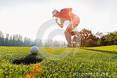 Asian woman golfer action to win after long putting golf ball on the green golf, sunset time, Stock Photo