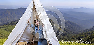 Asian woman greeting friend while on a solo trekking camp on the top of the mountain with small tent for weekend activities and Stock Photo