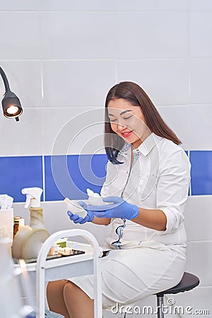 Asian woman gynecologist doctor in white coat looks into the frame Stock Photo