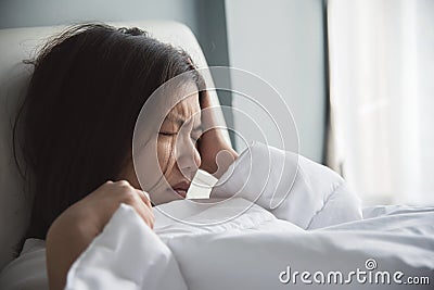 Asian woman having headache on her bed. Migraine. Illness, disease concept. Stock Photo