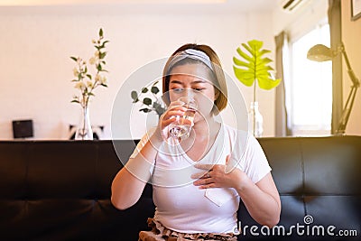 Asian woman having or symptomatic reflux acids,Gastroesophageal reflux disease,Drinking water Stock Photo