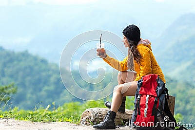 Asian women hiker or traveler with backpack adventure sitting and drinking ice coffee relax and rest on the mountain outdoor for d Stock Photo