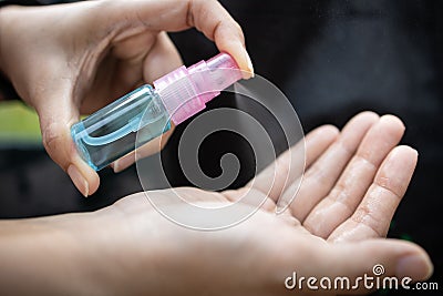 Asian woman hold a bottle of alcohol disinfectant,girl is spraying alcohol on her palms or hands to prevent infection of Covid-19 Stock Photo