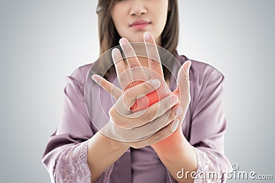 Asian woman holding her hand against gray background , Pain concept Stock Photo