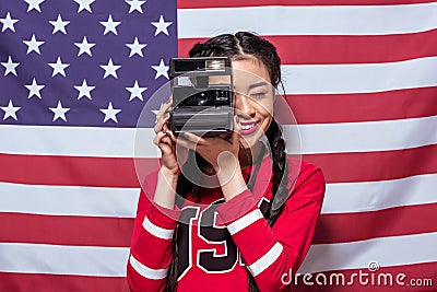 Asian woman holding retro photo camera with american flag behind Stock Photo