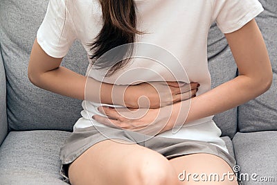 Asian woman holds her stomach with both hands. Stomach upset or pain during menstruation. Stock Photo