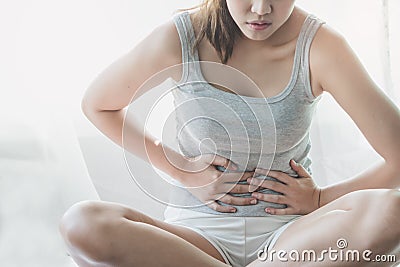 Asian woman laying on the bed suffering from abdominal pain. female suffering from period on the bed Stock Photo