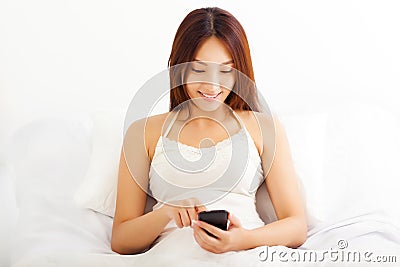 asian woman lying on bed using her smart phone in her bedr Stock Photo