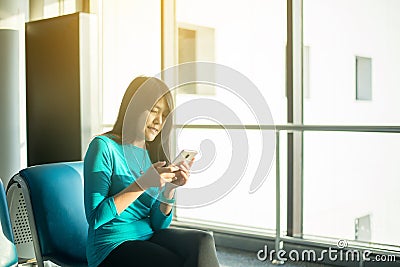 Asian woman passenger holding mobile phone and checking flight or online check in and travel planner at international airport Stock Photo