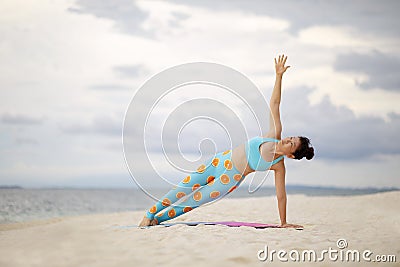 Asian woman playing side plank yoga pose on white sand beach Stock Photo