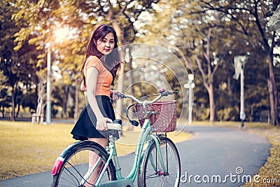 Asian woman portrait in public park with bicycle. People and Lifestyles concept. Relaxation and activity theme. Stock Photo
