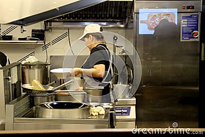 Asian woman prepares food behind a glass partition, food court at the central market. Editorial Stock Photo