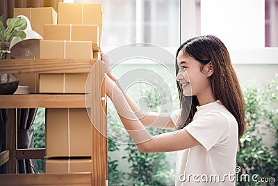 Asian woman put sticky memo paper note on parcel mail box and ready to send to customer. Business owner and Online shopping Stock Photo